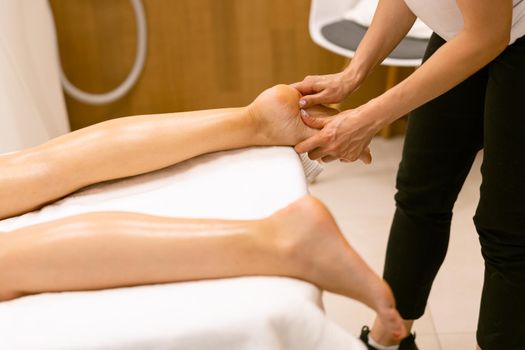 Middle-aged woman having a foot massage in a beauty salon. Body care treatment in a beauty centre.