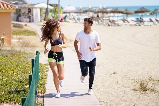 Young couple training together running on the beach