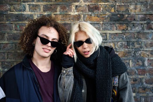 Young couple enjoying Camden town in front of a brick wall typical of London, UK