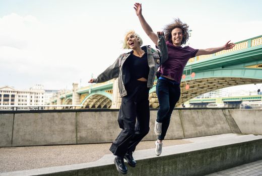 Funny couple junping near the Southwark bridge over River Thames, London. UK