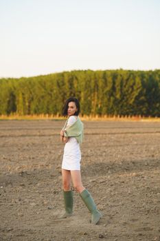 Pretty young Asian woman, walking in the countryside, wearing a white dress and green wellies.