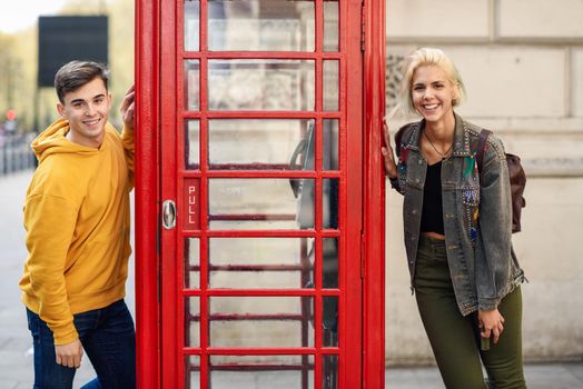 Young happy couple of friends near a classic British red phone booth