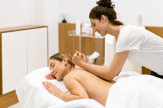 Middle-aged woman having a back massage in a beauty salon. Body care treatment in a beauty centre.