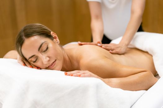 Middle-aged woman having a back massage in a beauty salon. Body care treatment in a beauty centre.