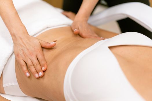 Middle-aged woman having a belly massage in a beauty salon. Body care treatment in a beauty centre.