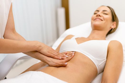 Middle-aged woman having a belly massage in a beauty salon. Body care treatment in a beauty centre.