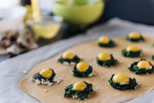 Step by step the chef prepares ravioli with ricotta cheese, yolks quail eggs and spinach with spices. The chef prepares the filling on the dough