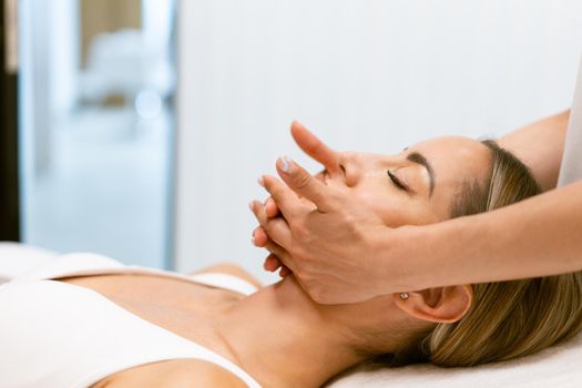 Middle-aged woman having a head massage in a beauty salon. Body care treatment in a beauty centre.