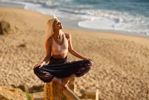 Woman enjoying the sunset on a beautiful beach in Cadiz, Andalusia, Spain. Young female sitting on beautiful stairs looking at the sea with golden light.