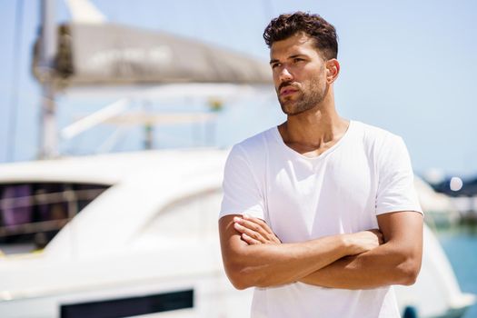 Fitness man, model of fashion, in sportswear outfit posing on waterfront harbour.