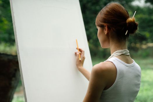 an artist in nature draws on an easel with a pencil. High quality photo