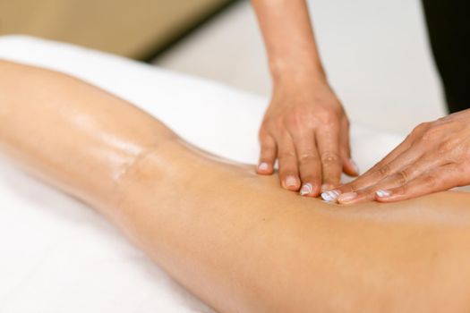 Woman receiving a leg massage with massage candle oil. Body care treatment in a beauty centre.