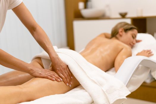 Woman receiving a leg massage with massage candle oil. Body care treatment in a beauty centre.