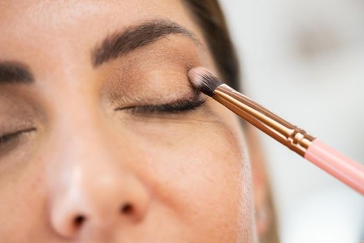 Close-up of a make-up artist applying eye shadow to her client. Beauty and Aesthetic concepts.