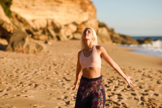 Woman enjoying the sunset on a beautiful beach in Cadiz, Andalusia, Spain. Young female opening arms and breathing the sea air.