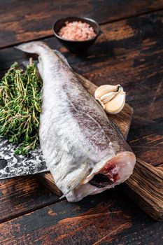 Fresh Raw cod or codfish fish on wooden board with cleaver. Dark Wooden background. Top view.