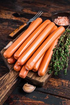 Frankfurter sausages on wooden cutting board. Dark Wooden background. Top view.