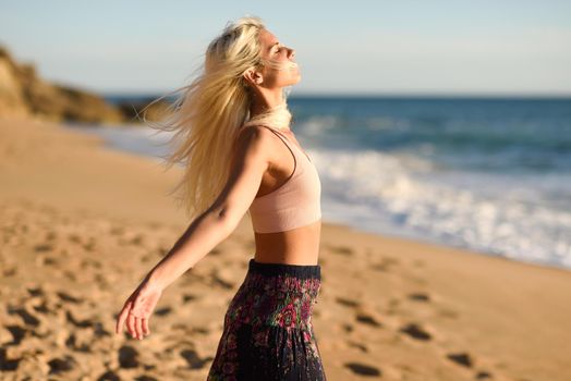 Woman enjoying the sunset on a beautiful beach in Cadiz, Andalusia, Spain. Young female opening arms and breathing the sea air.