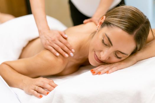 Middle-aged woman having a back massage in a beauty salon. Body care treatment in a beauty centre.