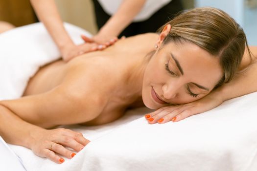 Middle-aged woman having a back massage in a beauty salon. Body care treatment in a beauty centre.