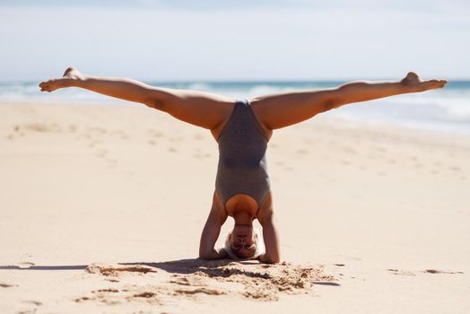 Caucasian woman practicing yoga at seashore. Young female raising arms in the beach in Cadiz, Andalusia, Spain.