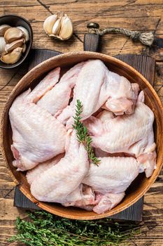 Raw chicken wings in a wooden plate with thyme and garlic. Wooden background. Top view.