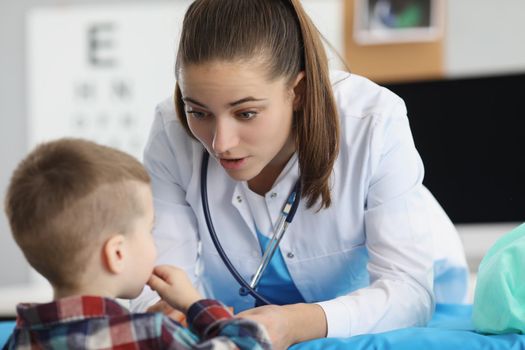 Portrait of pediatrician woman providing healthcare for kid patient in office, specialized clinic for children. Young qualified woman doctor with stethoscope. Medicine, healthcare concept