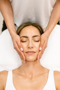Middle-aged woman having a head massage in a beauty salon. Body care treatment in a beauty centre.