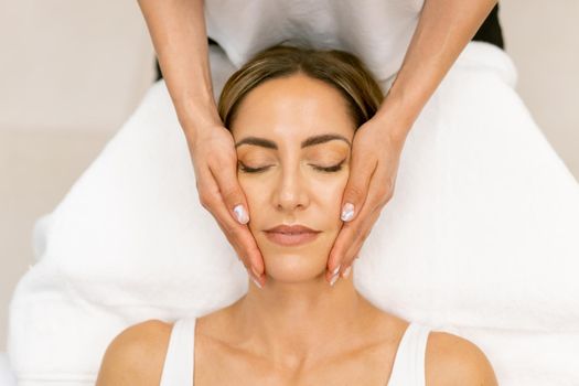 Middle-aged woman having a head massage in a beauty salon. Body care treatment in a beauty centre.