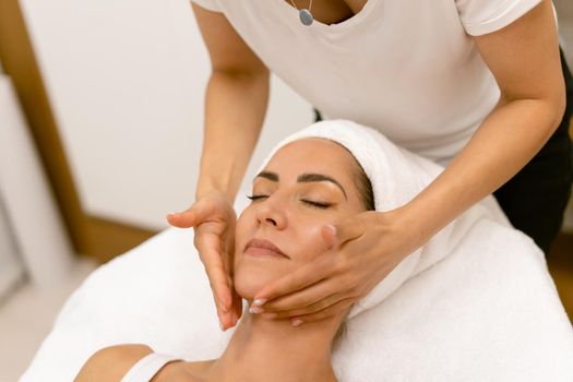 Middle-aged woman having a head massage in a beauty salon. Body care treatment in a beauty centre.