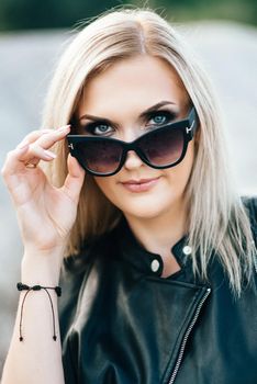 blonde girl in a black trouser suit with blue eyes on the background of a granite quarry from gray rubble