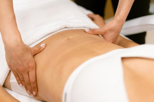 Middle-aged woman having a belly massage in a beauty salon. Body care treatment in a beauty centre.