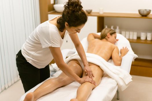 Woman receiving a leg massage with massage candle oil. Body care treatment in a beauty centre.