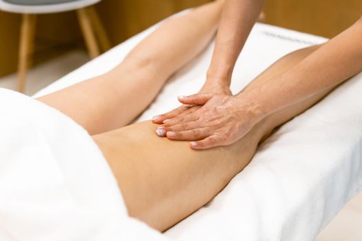 Woman receiving a leg massage with massage candle oil. Body care treatment in a beauty centre.