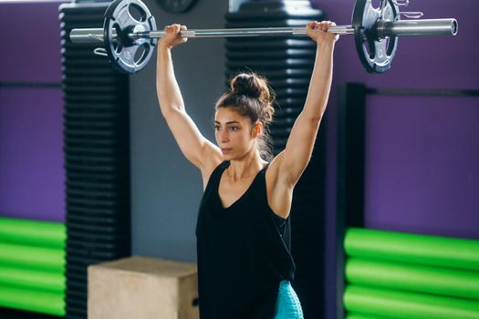 Athletic woman in gym lifting weights at the gym. Fitness concept.