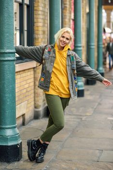 Young woman arms raised enjoying in urban background with modern hairstyle.