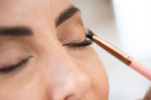 Close-up of a make-up artist applying eye shadow to her client. Beauty and Aesthetic concepts.