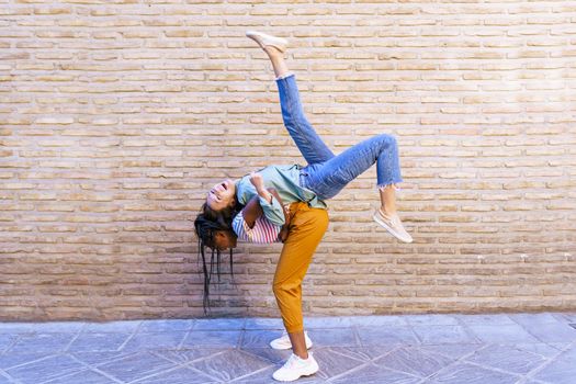 Funny multiethnic woman carrying her best friend piggyback outdoors