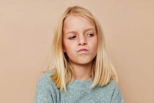 Beautiful little girl in a sweater, grimaces cropped view. High quality photo