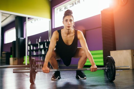 Athletic woman in gym lifting weights at the gym. Fitness concept.