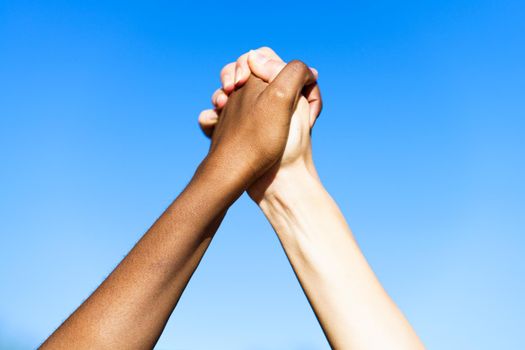 Close up of multiethnic women's hands together against blue sky.