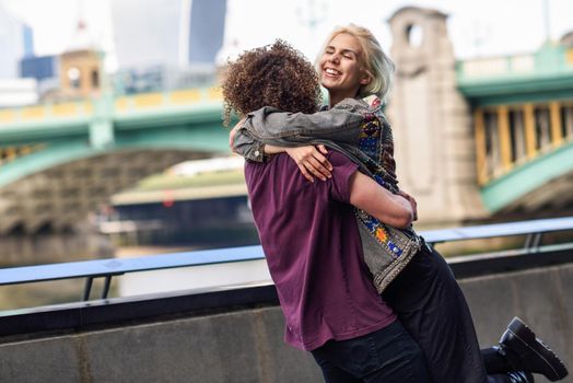 Happy couple hugging near the Southwark bridge over River Thames, London. UK