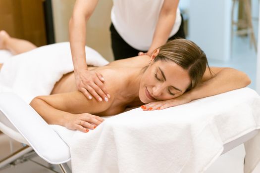 Middle-aged woman having a back massage in a beauty salon. Body care treatment in a beauty centre.