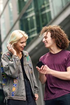 Happy couple using smartphone in urban background. Young man and woman wearing casual clothes in a London street.