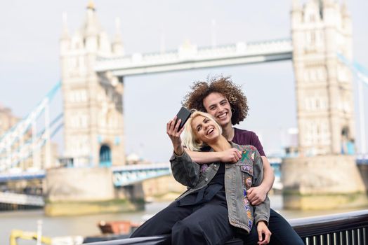 Happy couple taking selfie photograph at the Tower Bridge, River Thames, London. UK
