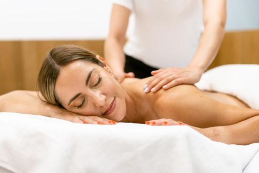 Middle-aged woman having a back massage in a beauty salon. Body care treatment in a beauty centre.