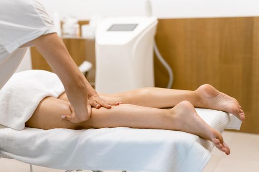 Middle-aged woman having a leg massage in a beauty salon. Body care treatment in a beauty centre.