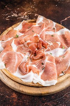 Prosciutto crudo ham on a wooden board. Dark background. Top View.