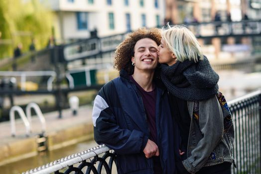 Happy couple having fun in Camden Town Little Venice, London. UK Young woman kissing her boyfriend in his face.