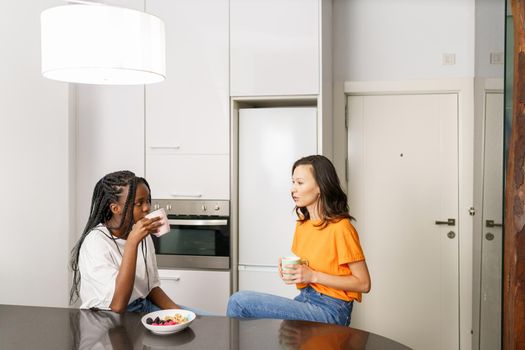 Two friends having a healthy snack while chatting at home. Multiethnic women.